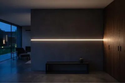 LED Unterputzprofil bündig in dunkler Wand verbaut Modernes Wohnzimmer mit einem flächenbündig in eine dunkelgraue Wand integrierten LED Unterputzprofil, das warmweißes Licht abgibt.