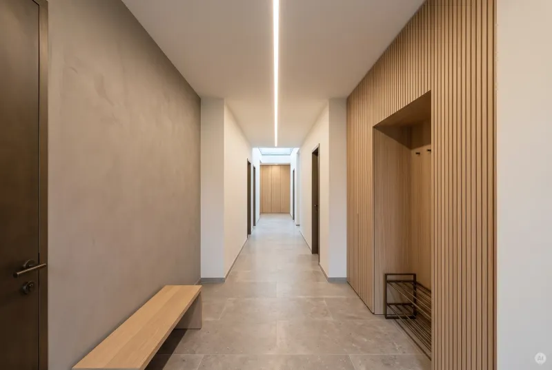 Langer moderner Flur mit flächenbündig verspachtelter LED-Lichtlinie in der Gipskartondecke und Akzentwand in Holzoptik